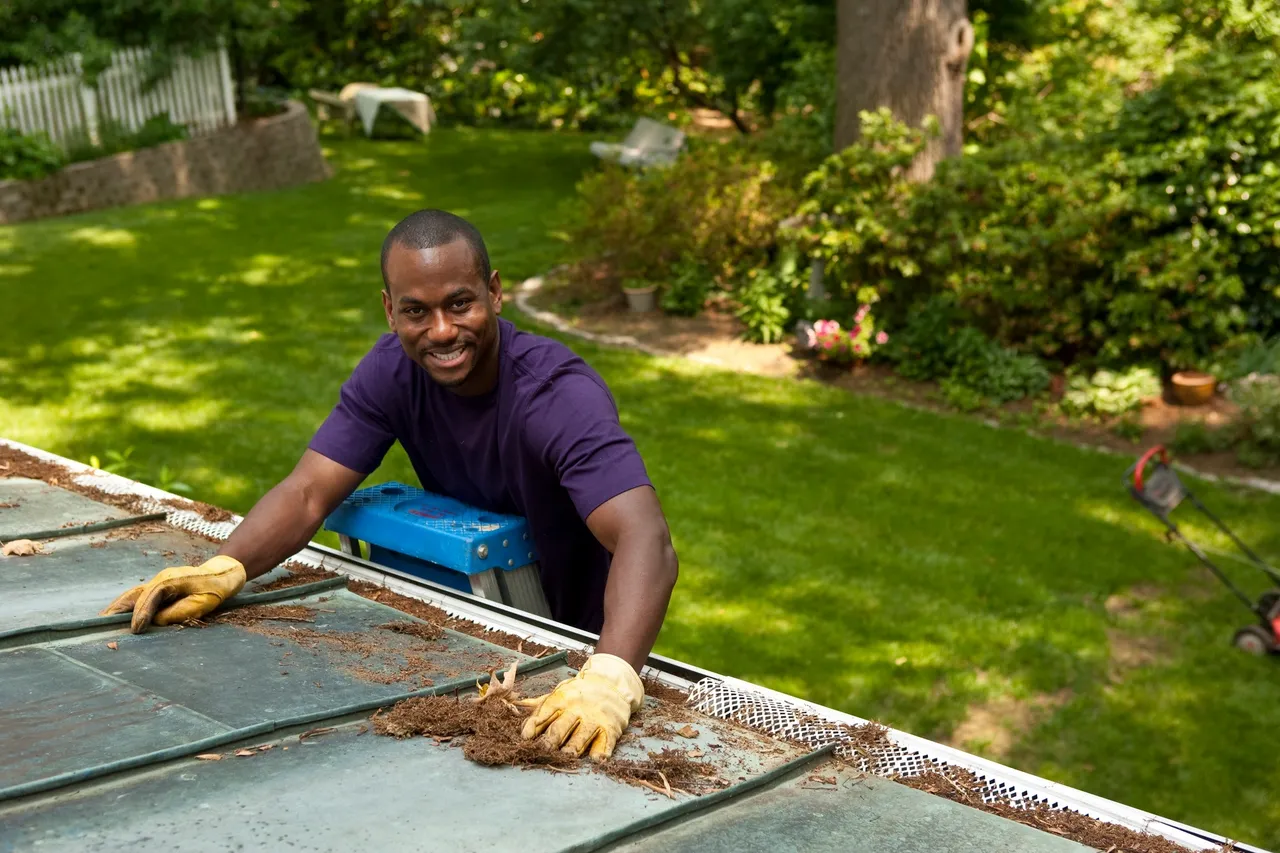 Man clearing debris from a gutter with leaf protection